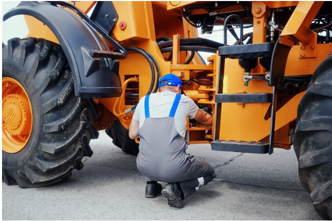 Mécanicien travaillant sur un grand tracteur avec hydrau mac