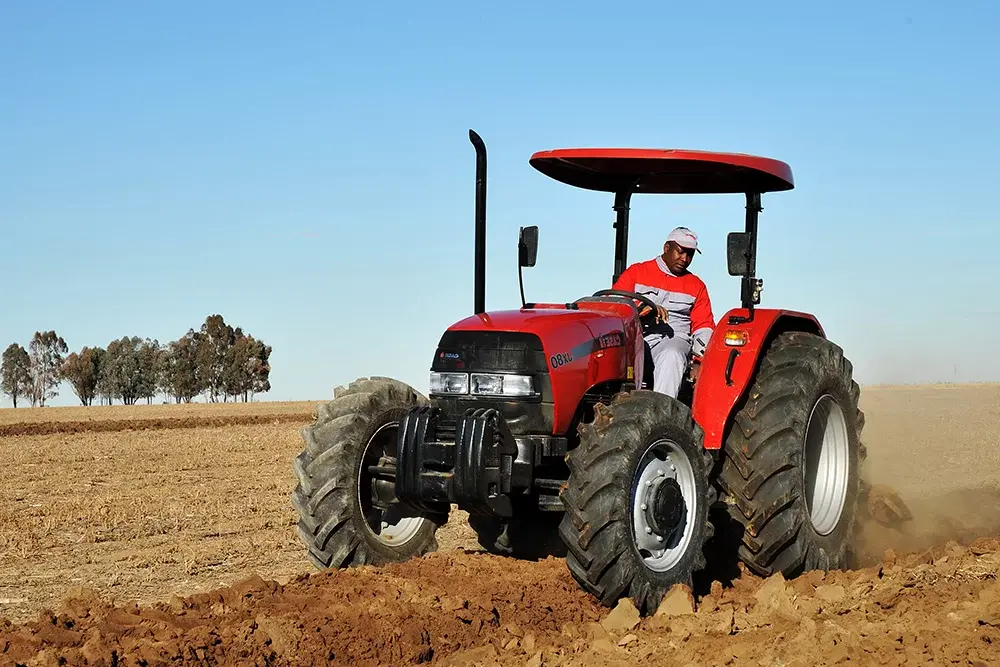Tracteur conduit par un homme dans un champ d'Import & Distribution